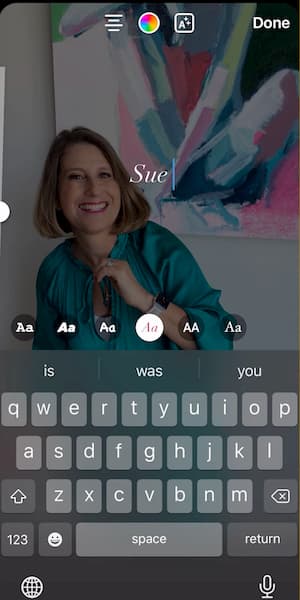 Sue B Zimmerman shares an Instagram Story that shows her smiling and wearing a teal blouse in front of a colorful painting with text that says Sue overlapping it.